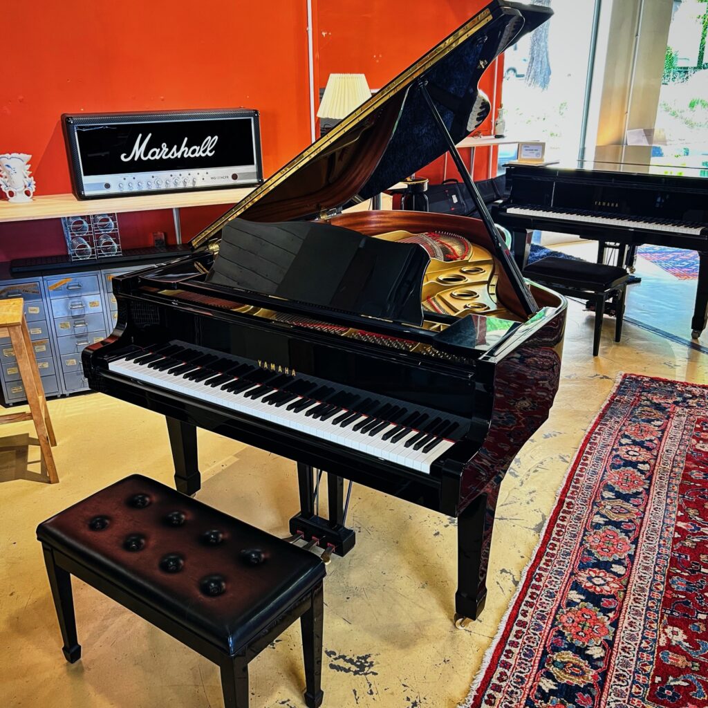 Piano à queue Yamaha G3 d’occasion noir brillant sur fond de tapis persan, en magasin de piano à Caen
