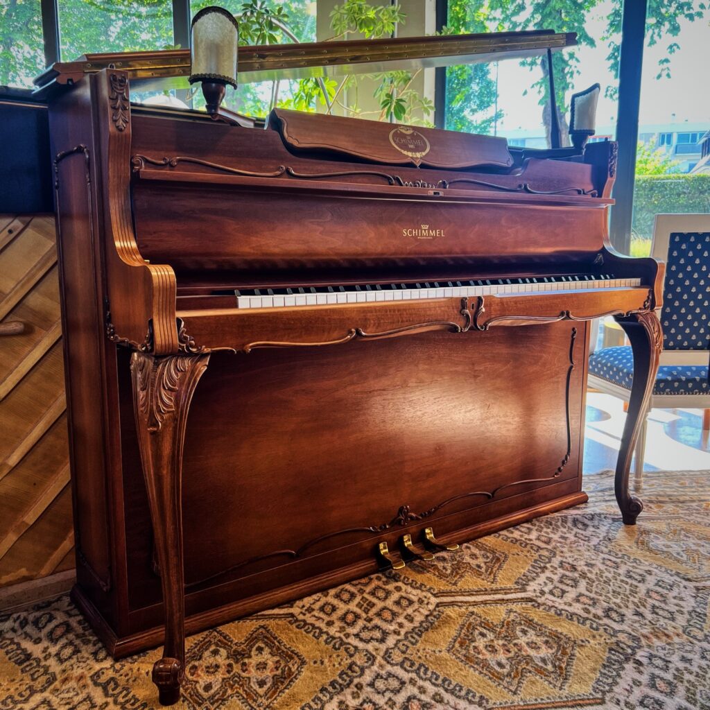 Piano droit Schimmel style Louis XV d’occasion en noyer, trois pédales, meuble sculpté.