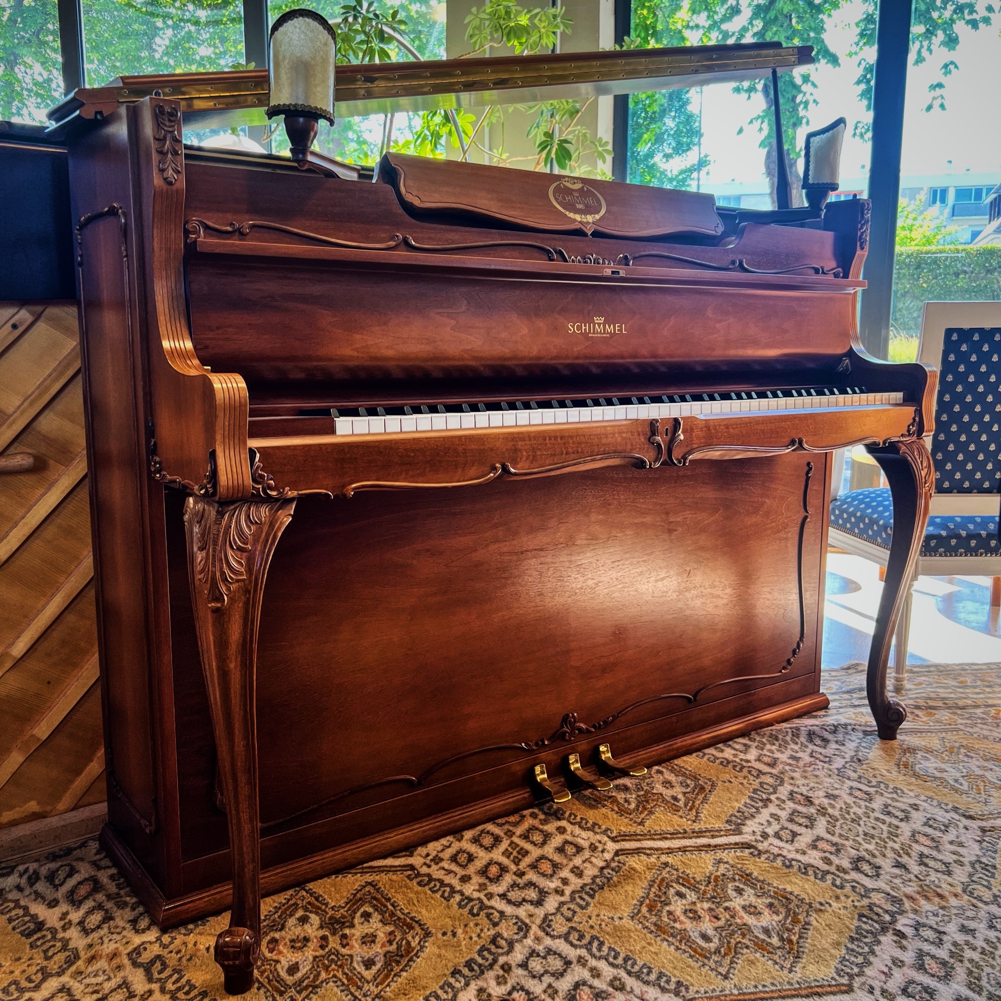 Piano droit Schimmel style Louis XV d’occasion en noyer, trois pédales, meuble sculpté.