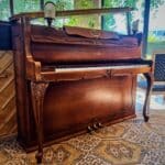 Piano acoustique Schimmel en bois sculpté – idéal pour débuter le piano avec un vrai toucher.