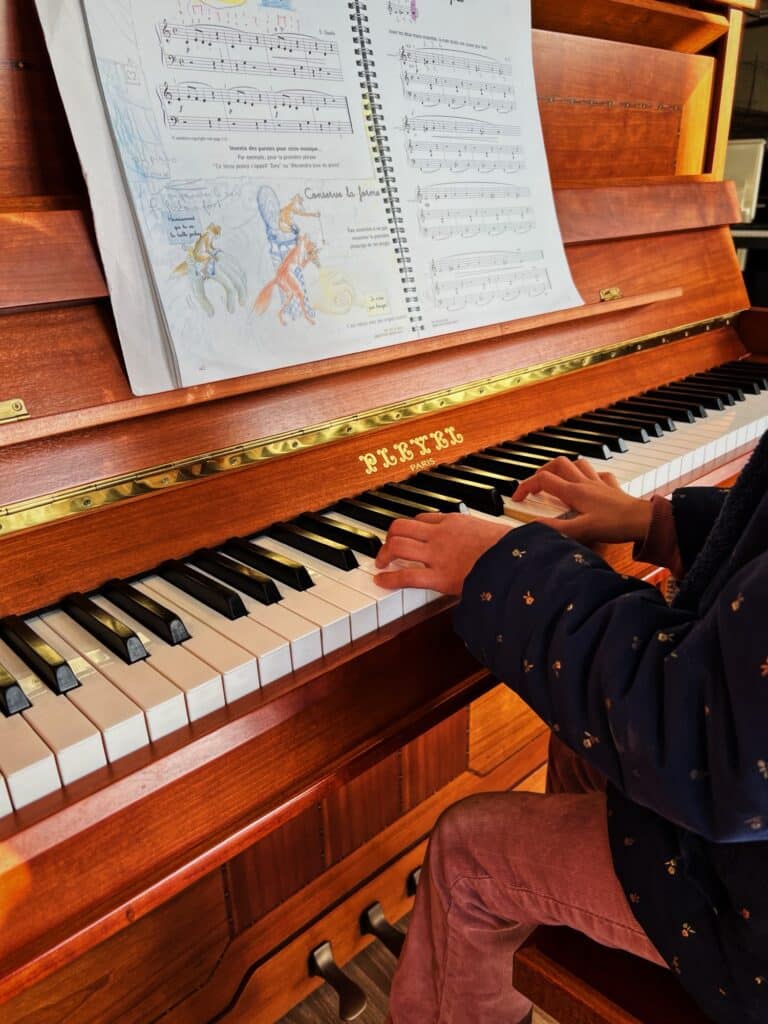 Enfant jouant un piano droit Pleyel avec méthode illustrée – atelier Bonnaventure à Caen