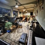 Vue d’ensemble du showroom Bonnaventure Piano à Caen avec pianos droits, pianos à queue et ambiance industrielle chaleureuse