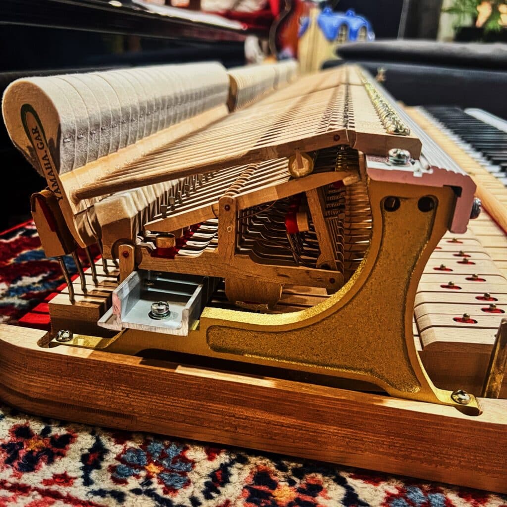 Vue rapprochée de la mécanique d’un piano Yamaha G2, avec marteaux et échappement exposés