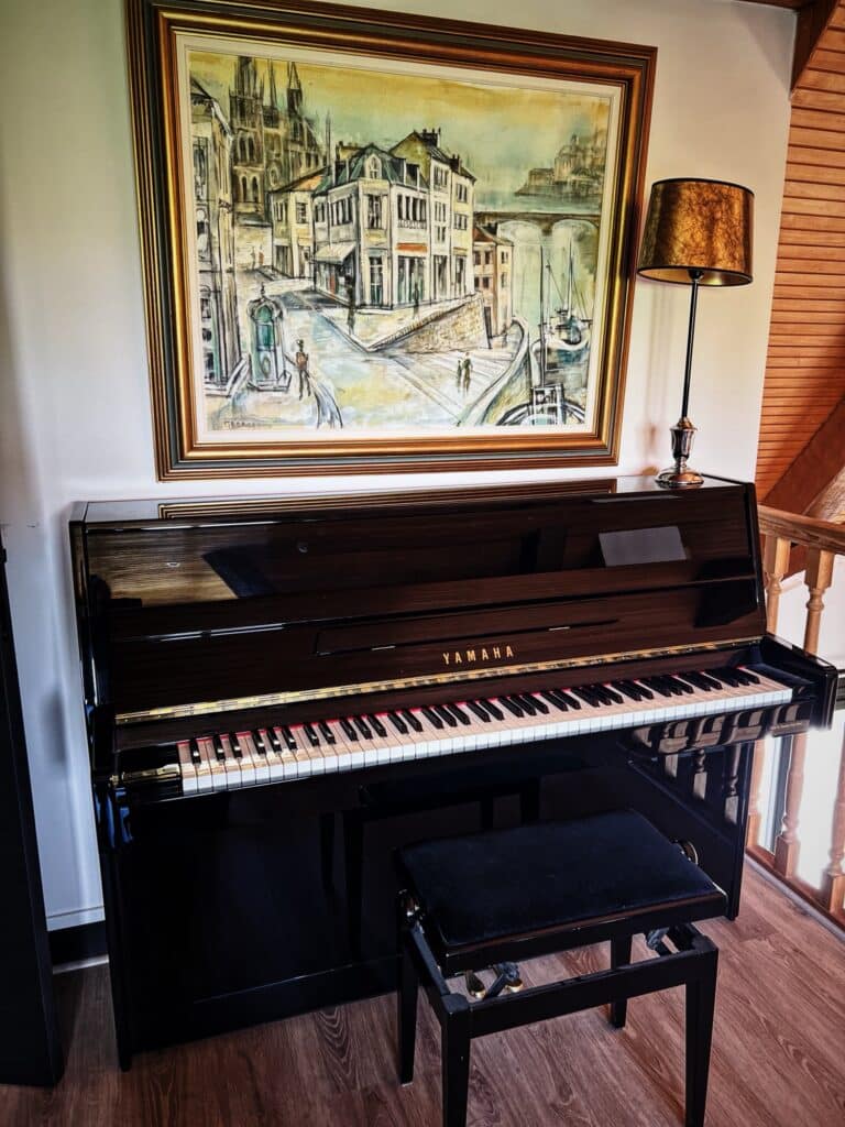Piano Yamaha C108 noir brillant d’occasion, modèle japonais compact dans intérieur chaleureux