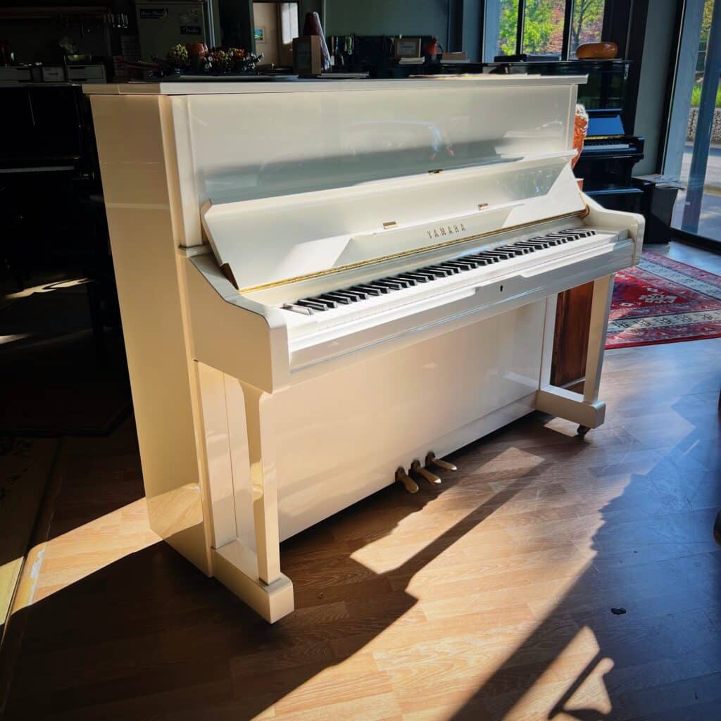 Piano droit noir 121 cm vu de profil dans le showroom Bonnaventure Piano à Caen, illustrant les dimensions et la profondeur d’un instrument acoustique.