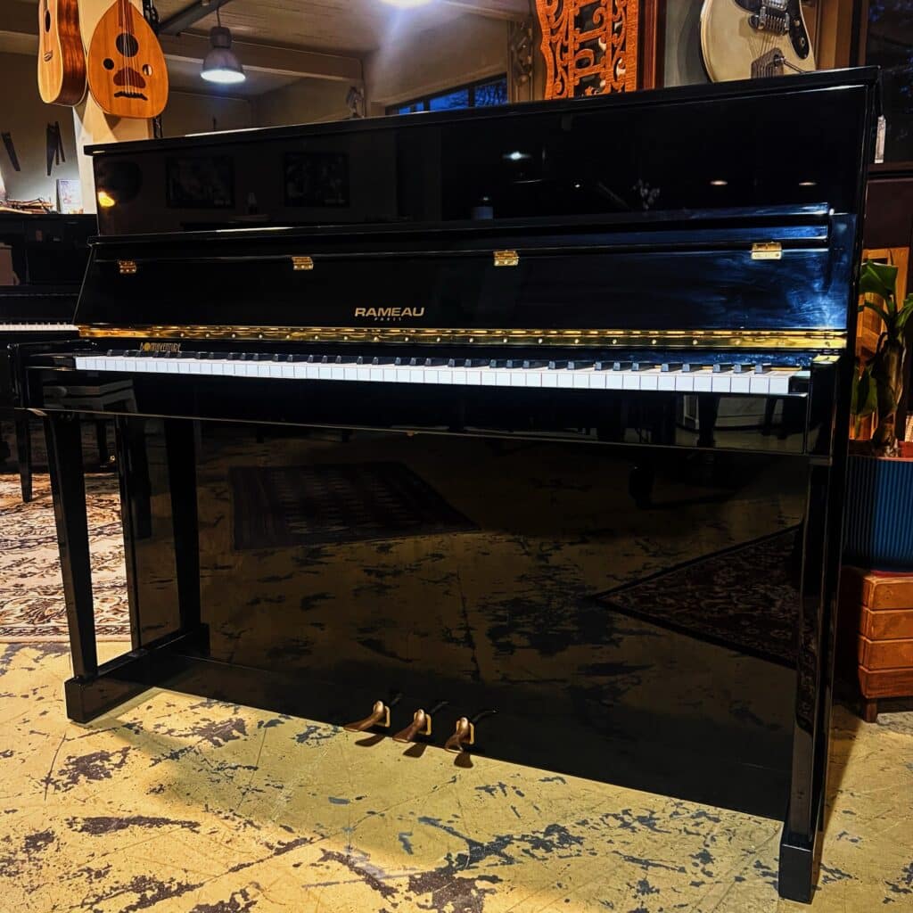 Piano droit Rameau 116 d’occasion noir brillant, fabrication française à Alès en 1991, hauteur 116 cm, cordes basses filées neuves.